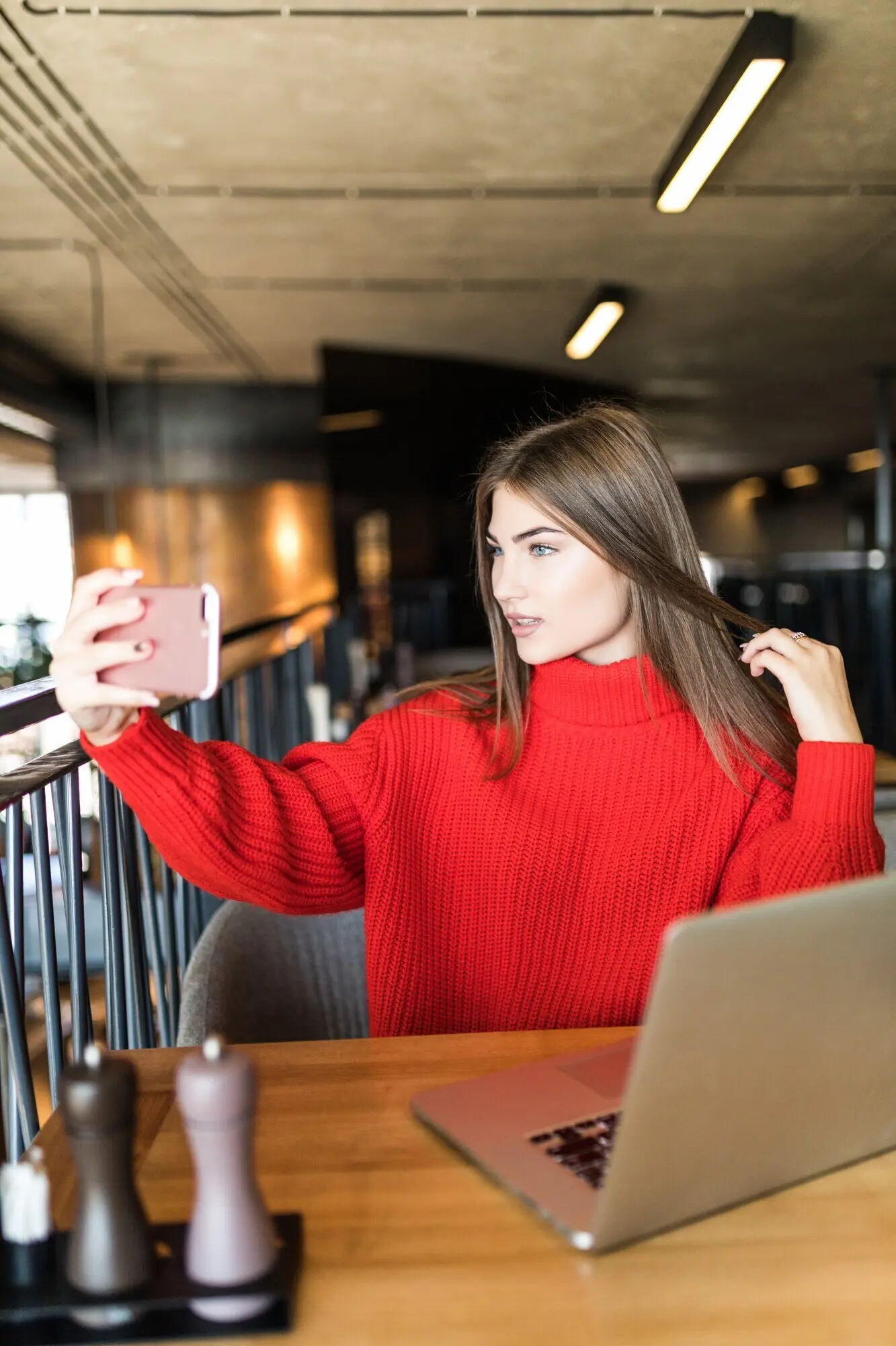 Улыбающаяся женщина‑фрилансер делает селфи на телефон или совершает видеозвонок — рабочий день свободной молодой женщины или студентки с ноутбуком.